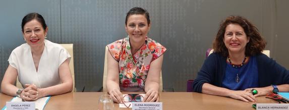 Tres mujeres sentadas en una mesa posando para la foto. 