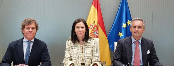 Imagen de tres personas en una sala de reuniones posando para una foto.