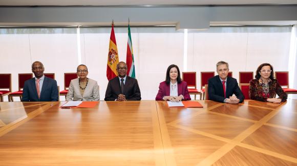 Un grupo de seis personas sentadas en una mesa, posando para la cámara. 
